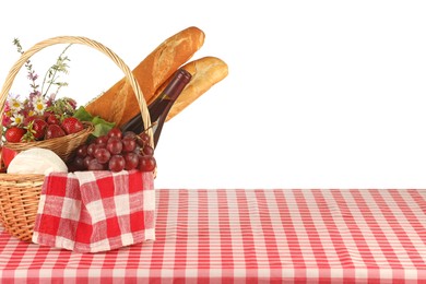 Photo of Picnic wicker basket with checkered napkin, food and bottle of wine on table against white background. Space for text