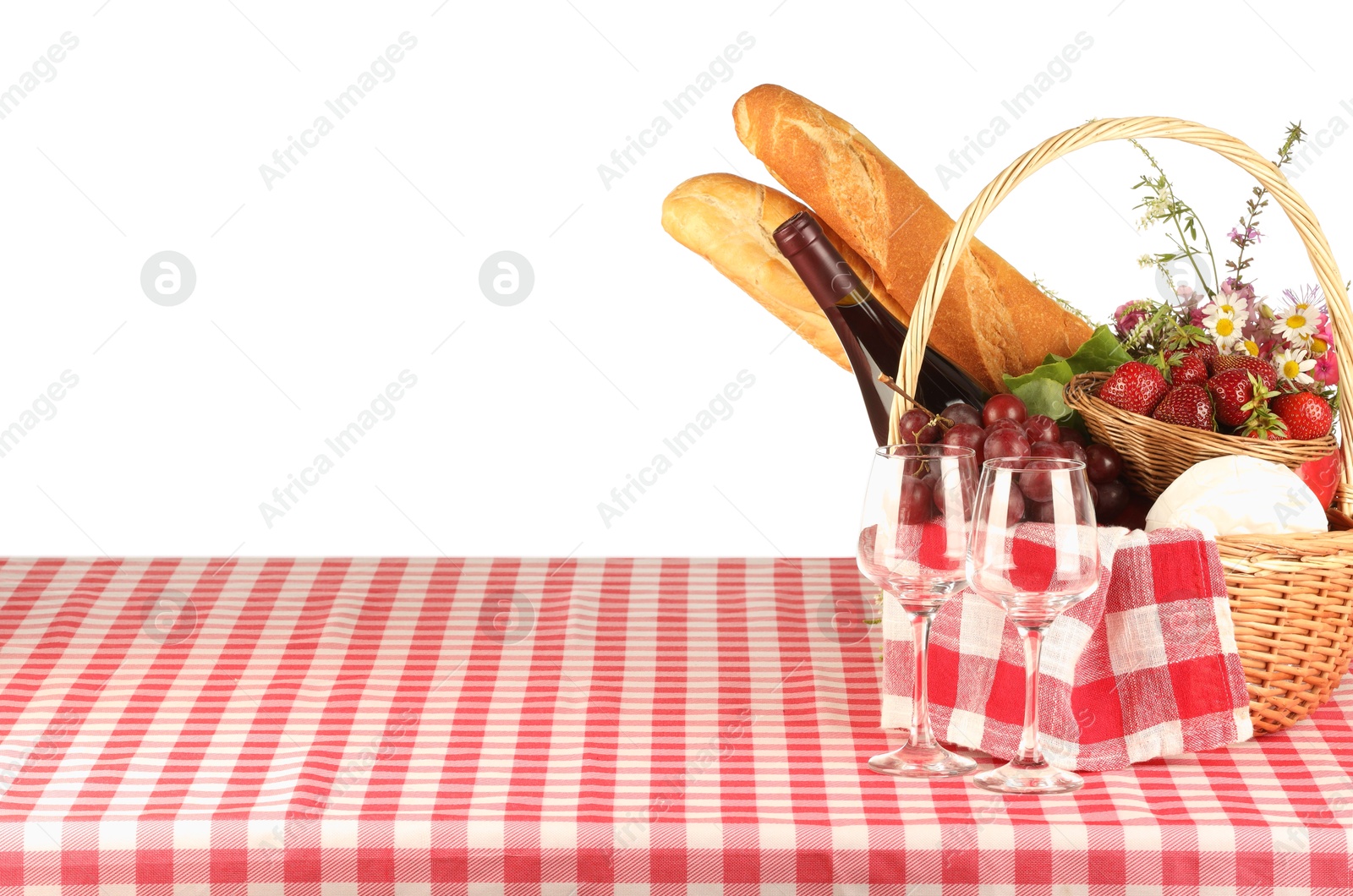 Photo of Picnic wicker basket with checkered napkin, food and bottle of wine on table against white background. Space for text