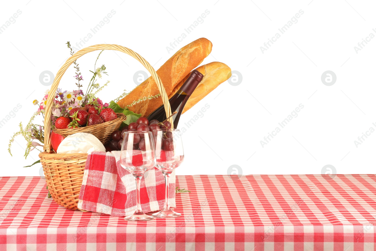 Photo of Picnic wicker basket with checkered napkin, food and bottle of wine on table against white background. Space for text