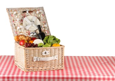 Photo of Picnic wicker basket with food, tableware and bottle of wine on table against white background. Space for text