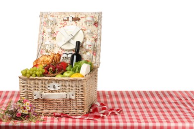 Picnic wicker basket with food, tableware and bottle of wine on table against white background. Space for text