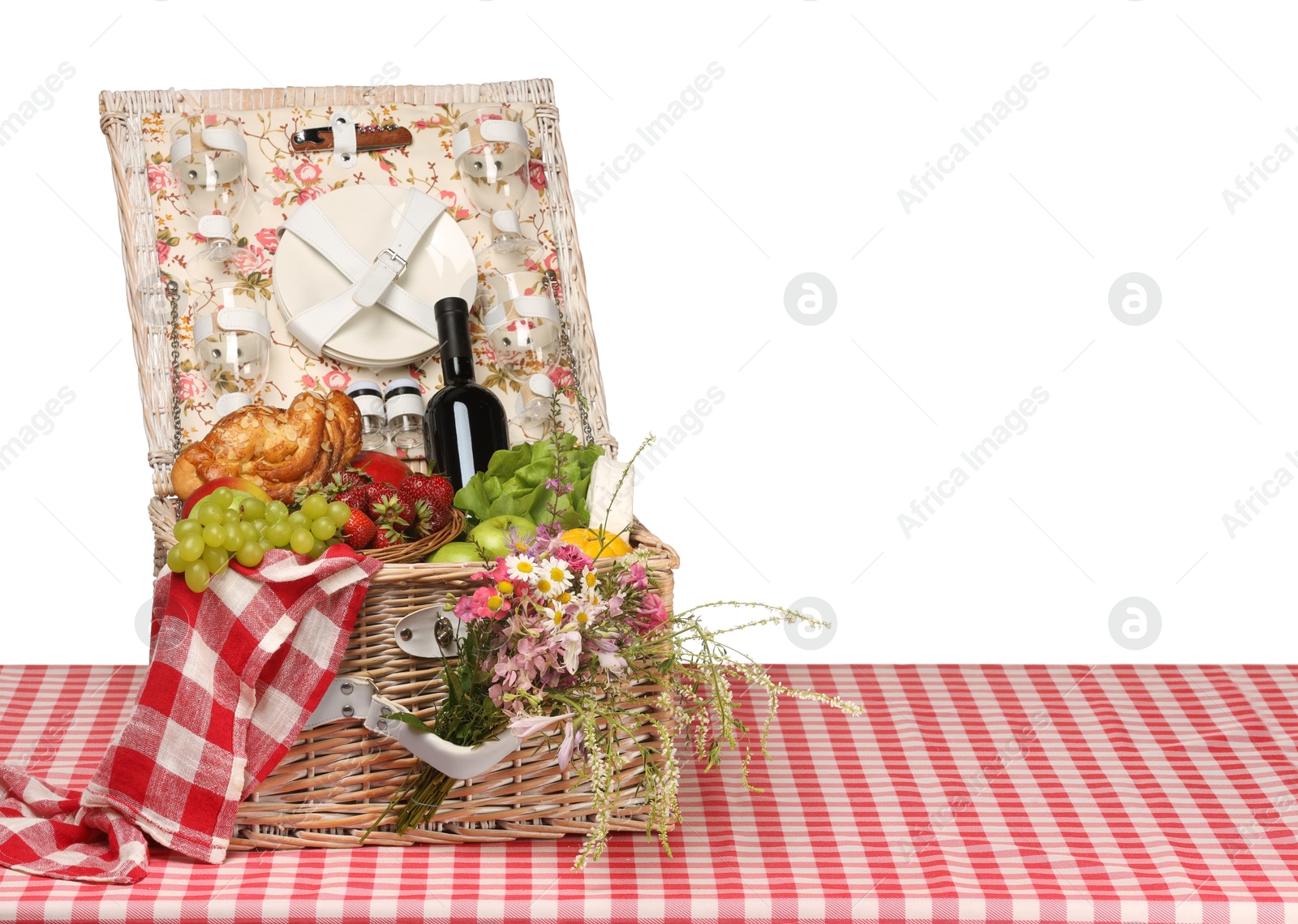 Photo of Picnic wicker basket with food, tableware, bottle of wine and flowers on table against white background. Space for text