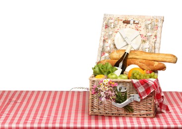 Photo of Picnic wicker basket with food, tableware, bottle of wine and flowers on table against white background. Space for text