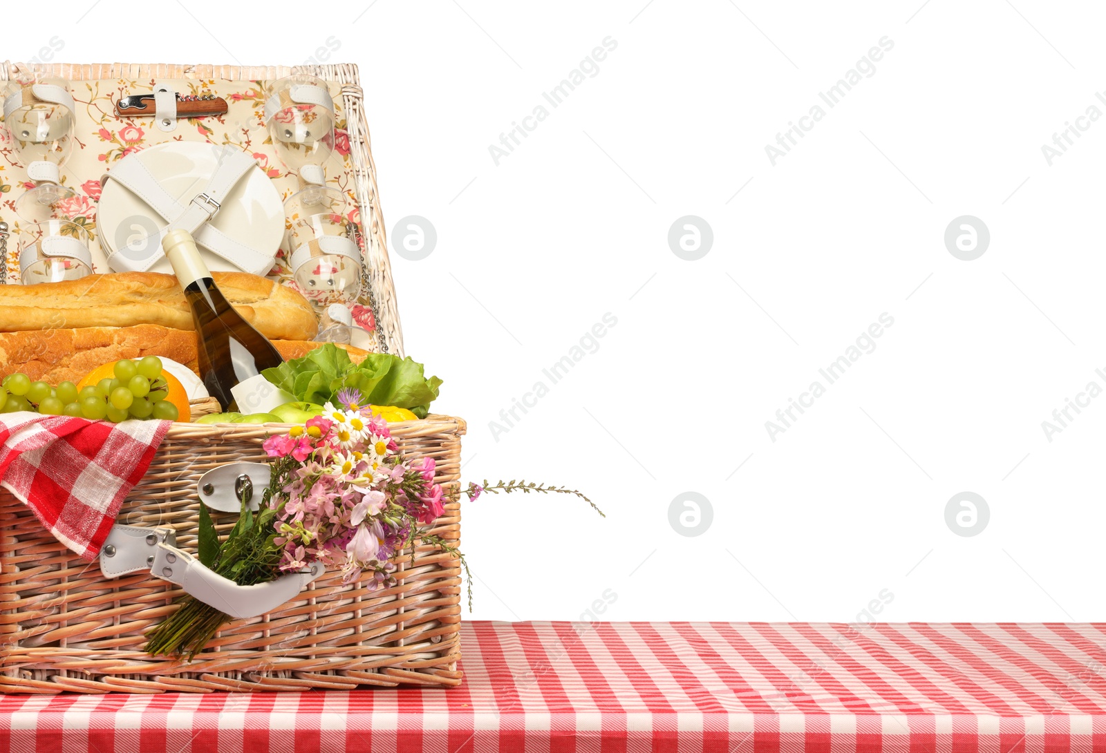 Photo of Picnic wicker basket with food, tableware, bottle of wine and flowers on table against white background. Space for text