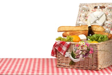 Photo of Picnic wicker basket with food, tableware, bottle of wine and flowers on table against white background. Space for text