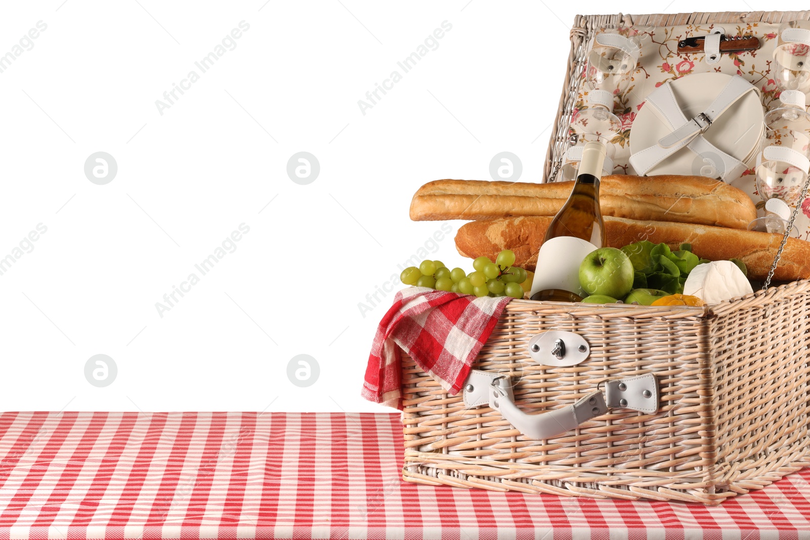 Photo of Picnic wicker basket with food, tableware, bottle of wine and napkin on table against white background. Space for text