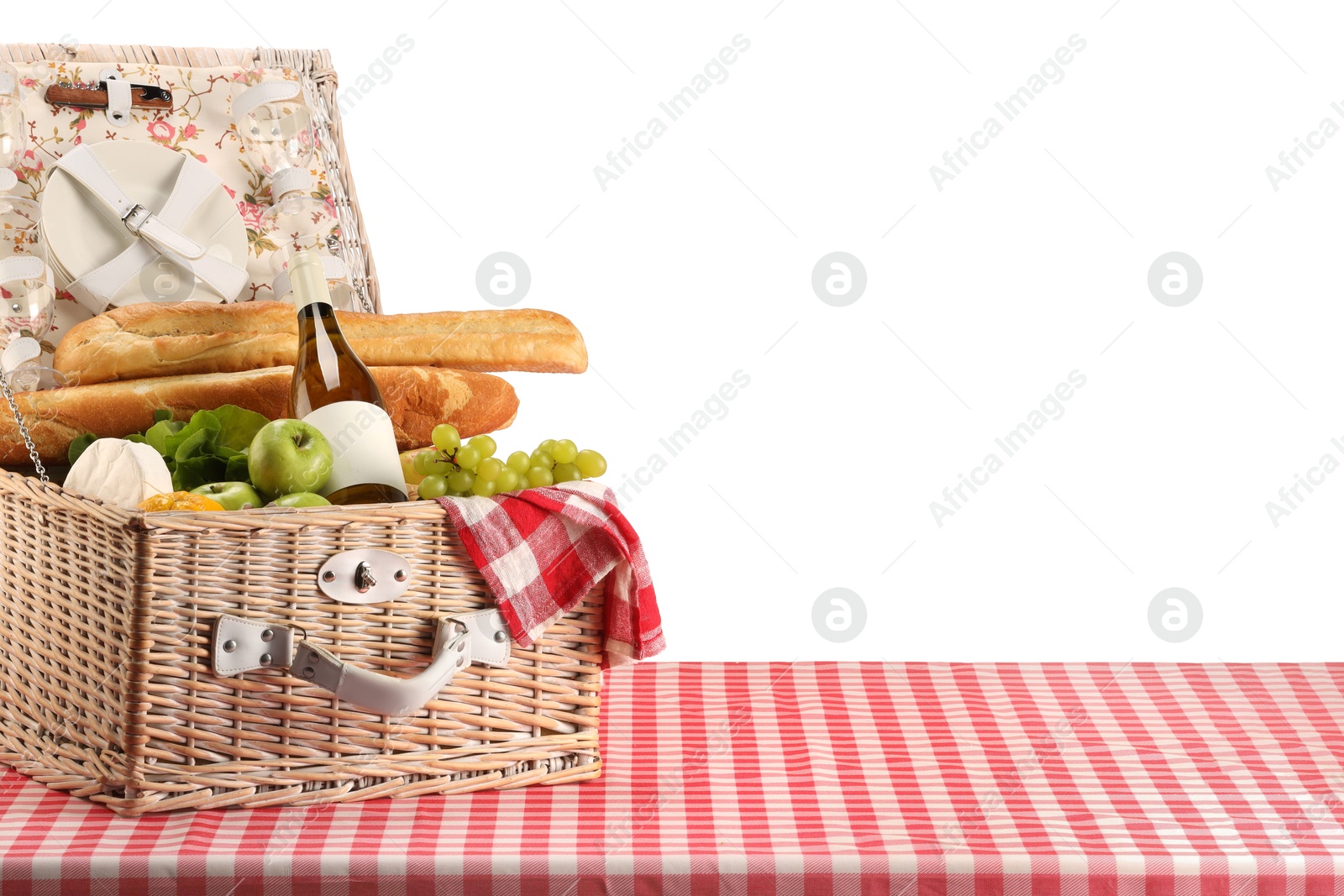 Photo of Picnic wicker basket with food, tableware, bottle of wine and napkin on table against white background. Space for text