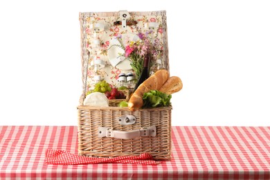 Photo of Picnic wicker basket with food, tableware, bottle of wine and flowers on table against white background