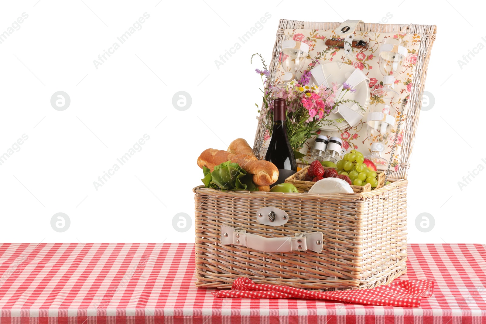 Photo of Picnic wicker basket with food, tableware, bottle of wine and flowers on table against white background. Space for text