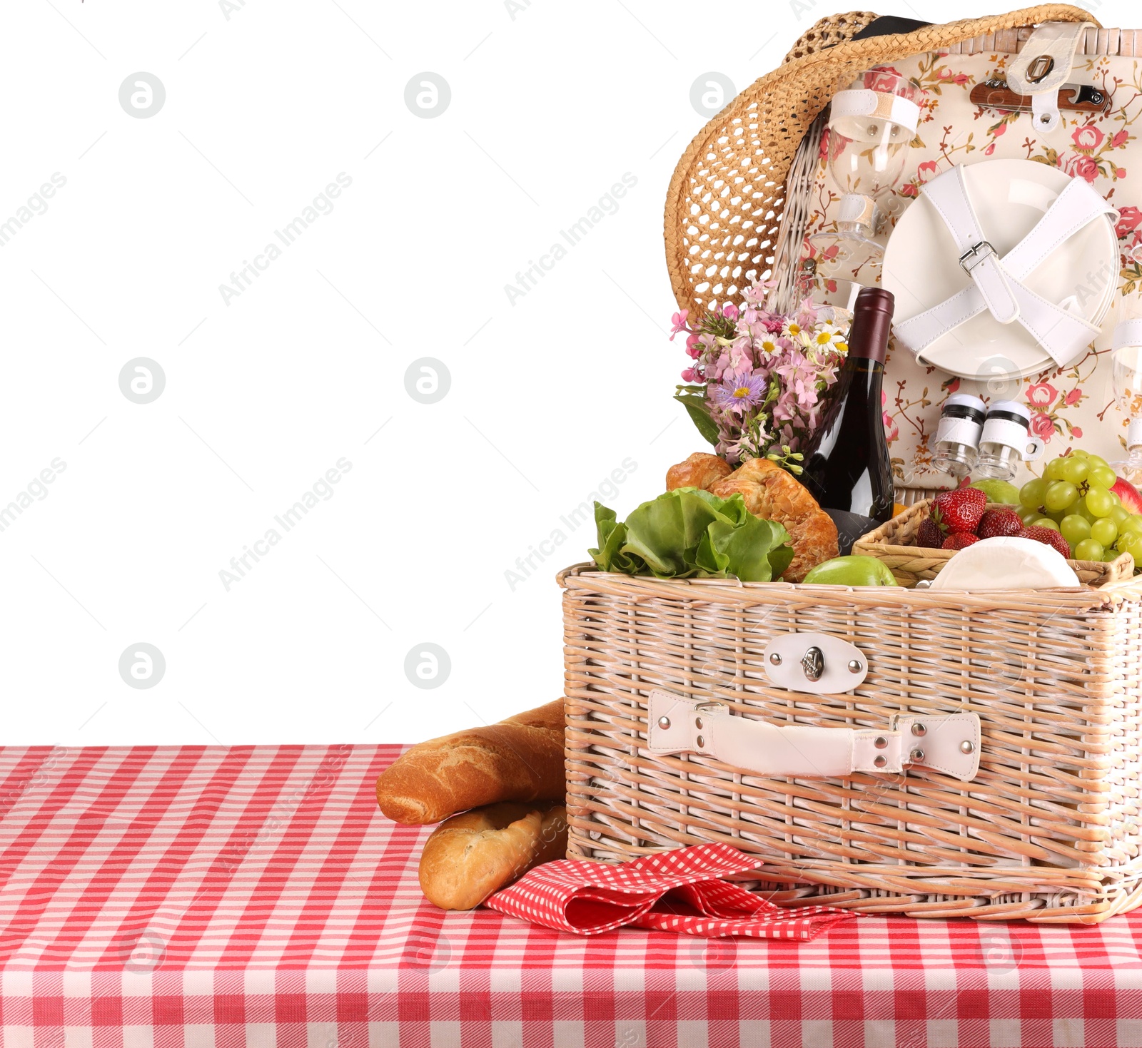 Photo of Picnic wicker basket with food, tableware, bottle of wine and flowers on table against white background. Space for text