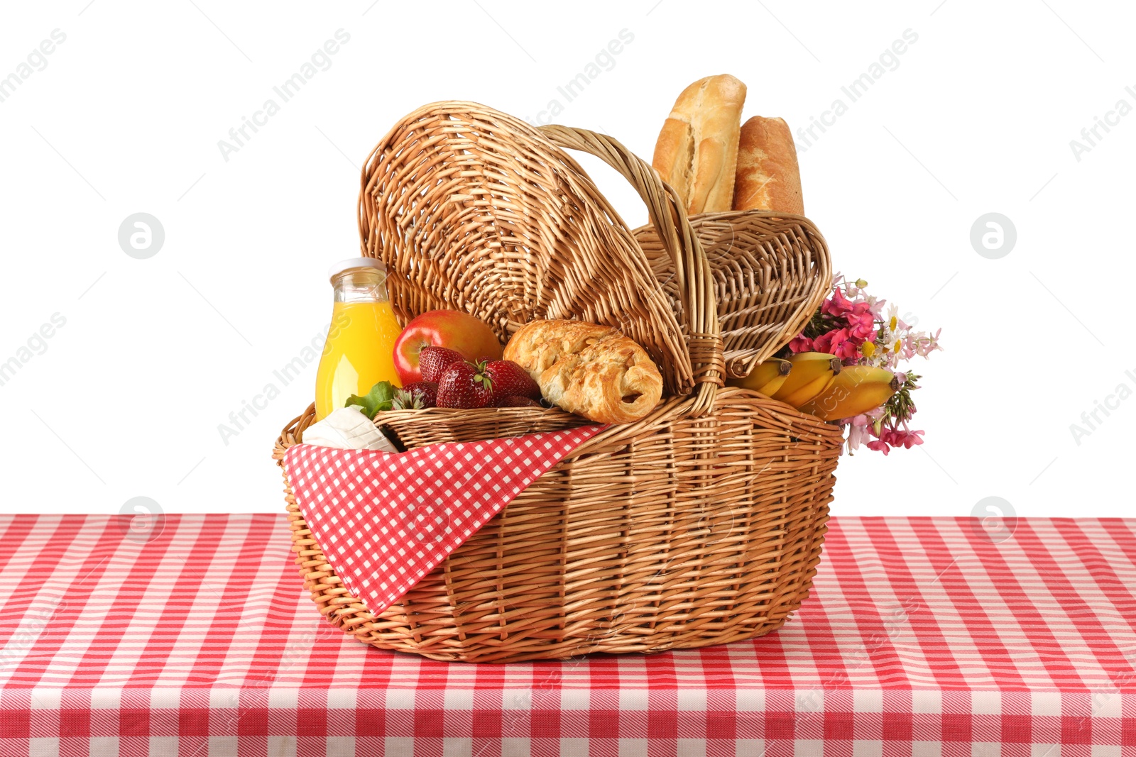 Photo of Picnic wicker basket with food, bottle of juice and flowers on table against white background