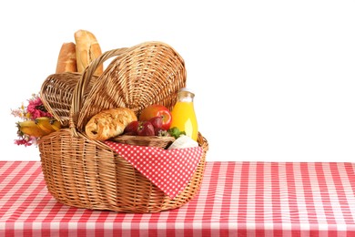 Photo of Picnic wicker basket with food, bottle of juice and flowers on table against white background. Space for text