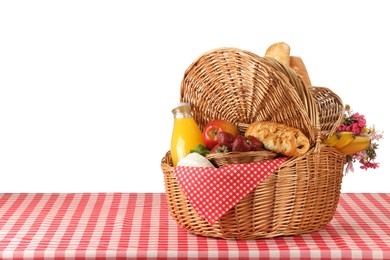 Photo of Picnic wicker basket with food, bottle of juice and flowers on table against white background. Space for text