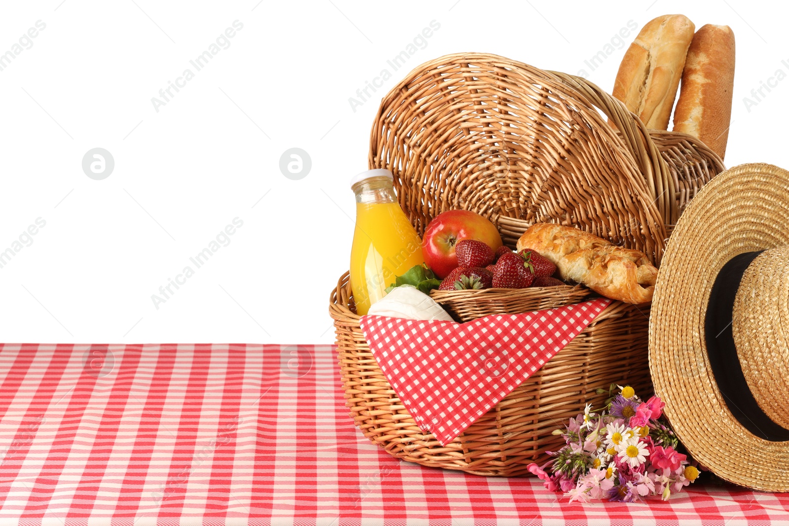 Photo of Picnic wicker basket with food, bottle of juice and flowers on table against white background. Space for text