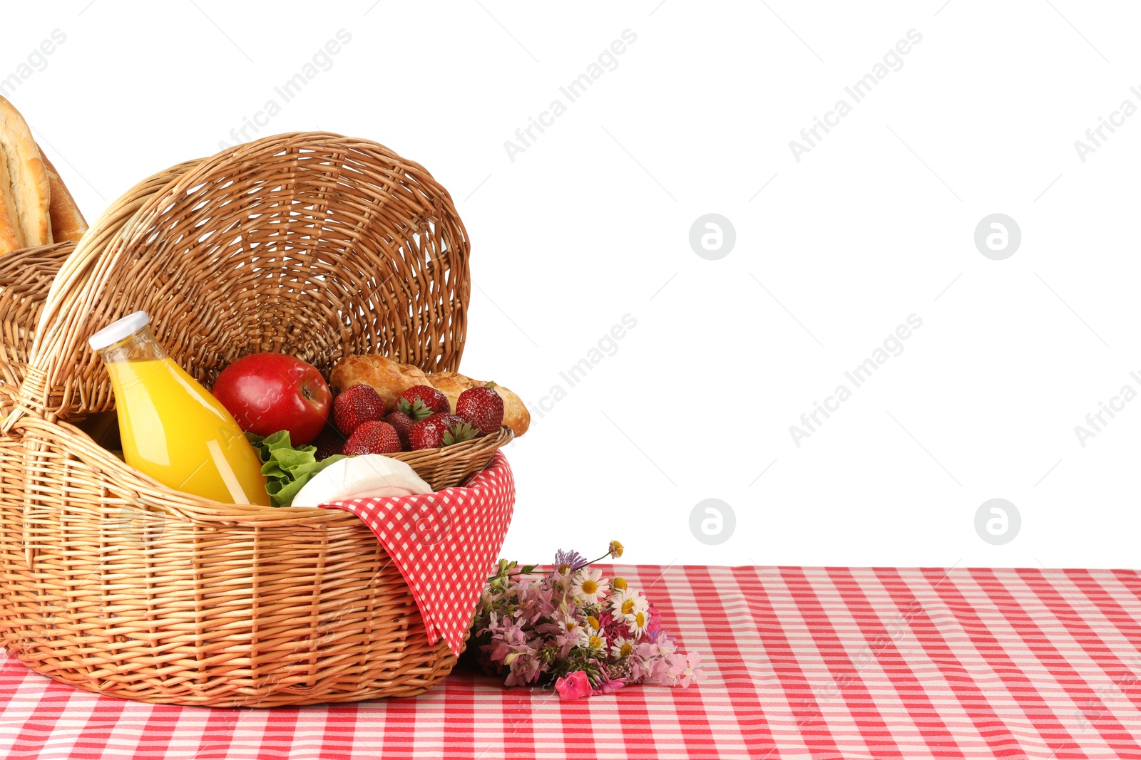 Photo of Picnic wicker basket with food, bottle of juice and flowers on table against white background. Space for text