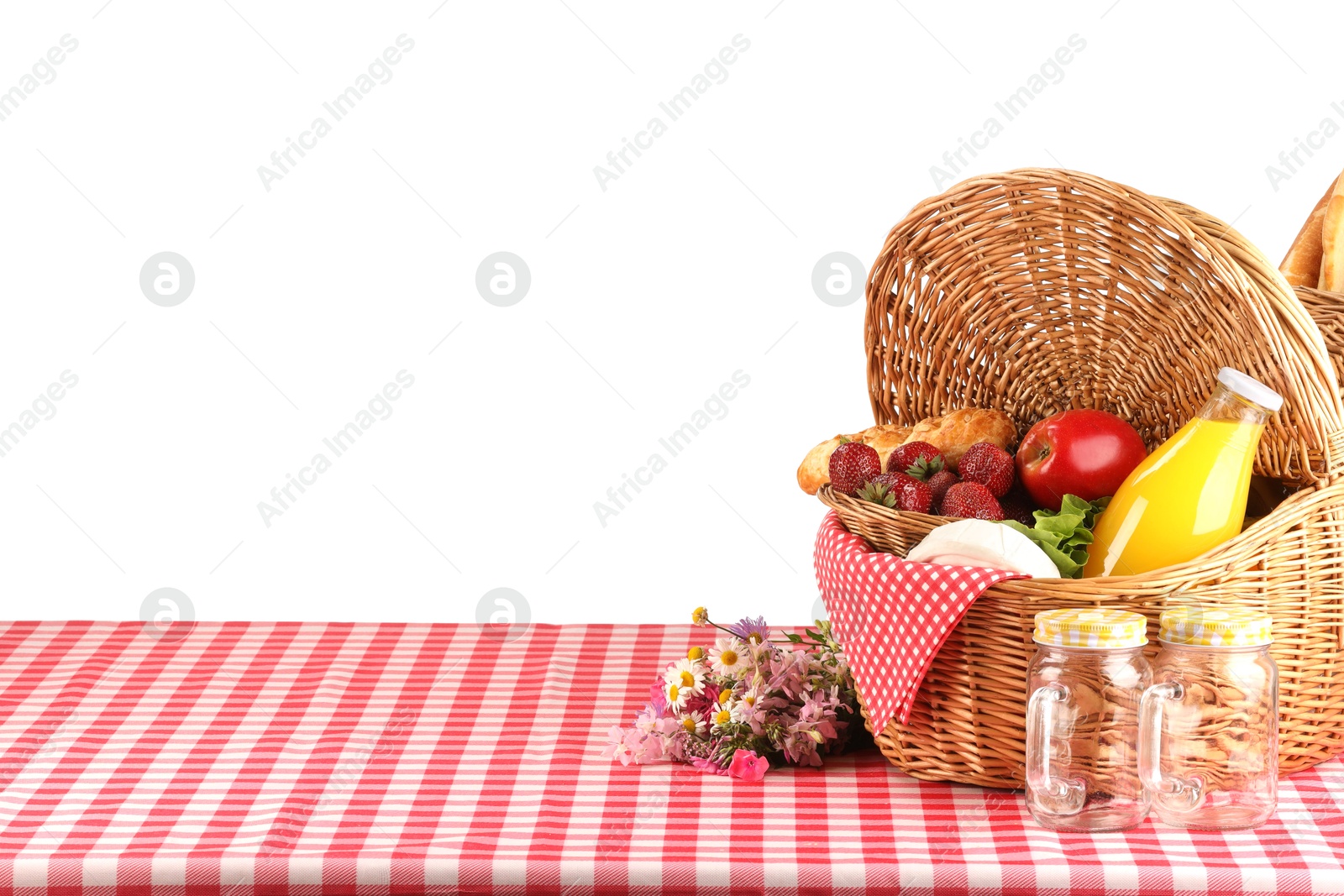 Photo of Picnic wicker basket with food, bottle of juice and flowers on table against white background. Space for text