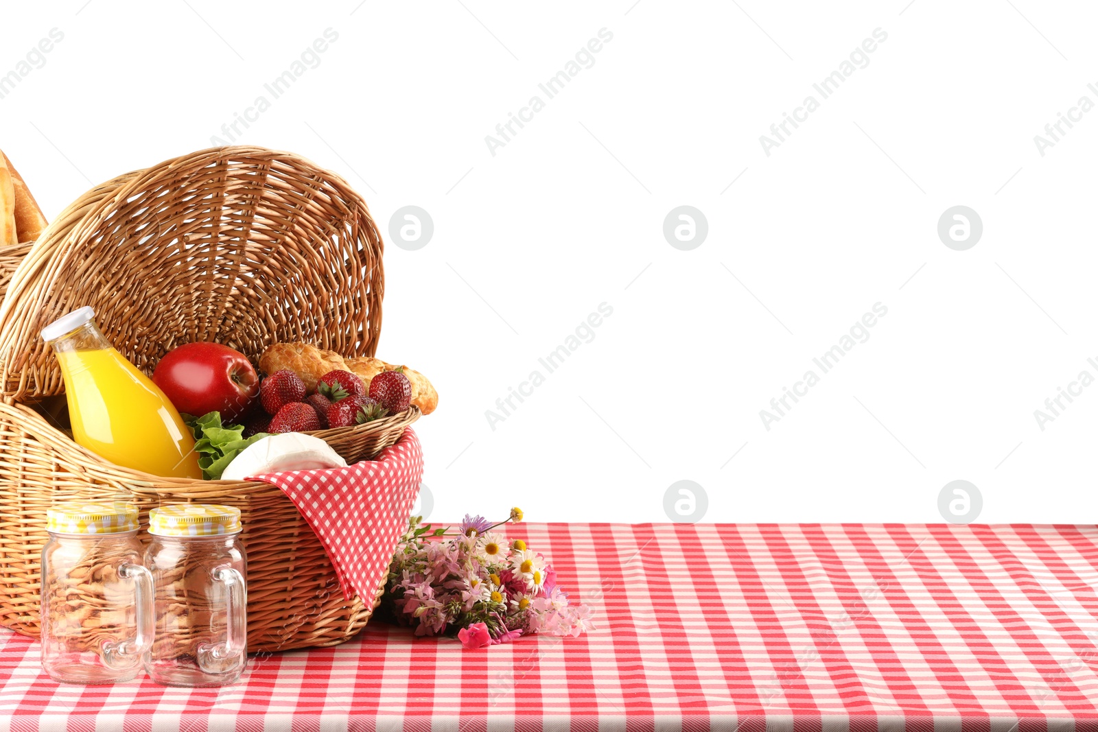 Photo of Picnic wicker basket with food, bottle of juice and flowers on table against white background. Space for text