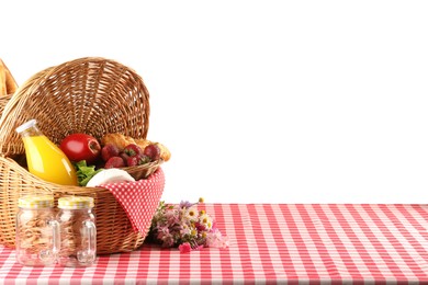 Photo of Picnic wicker basket with food, bottle of juice and flowers on table against white background. Space for text