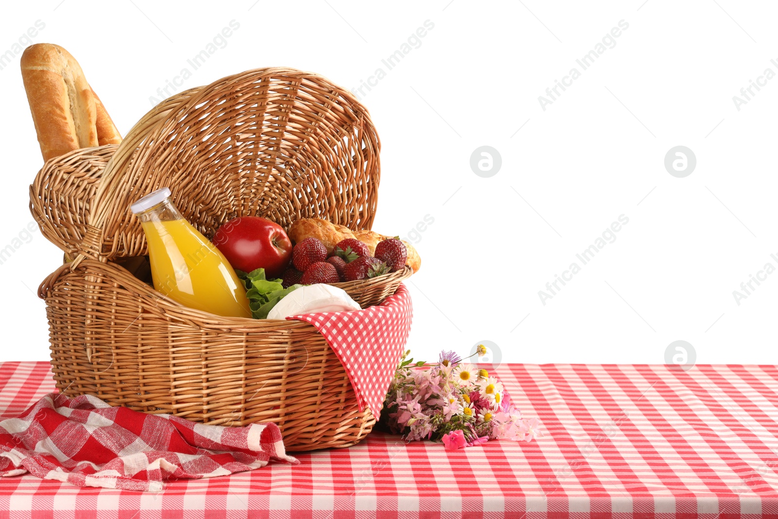 Photo of Picnic wicker basket with food, bottle of juice and flowers on table against white background. Space for text