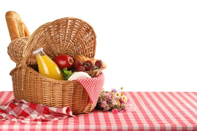 Picnic wicker basket with food, bottle of juice and flowers on table against white background. Space for text