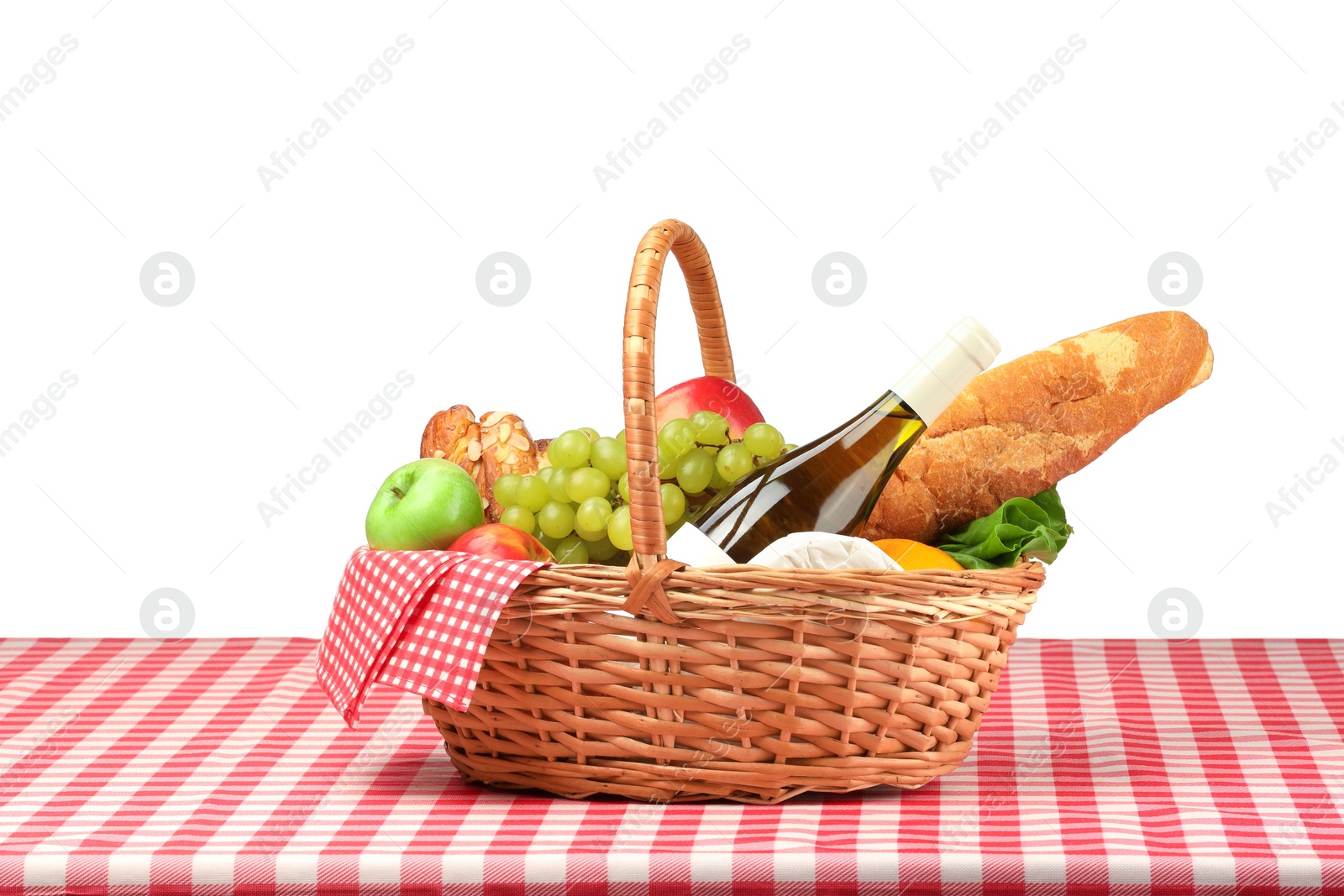 Photo of Picnic wicker basket with food, bottle of wine and napkin on table against white background