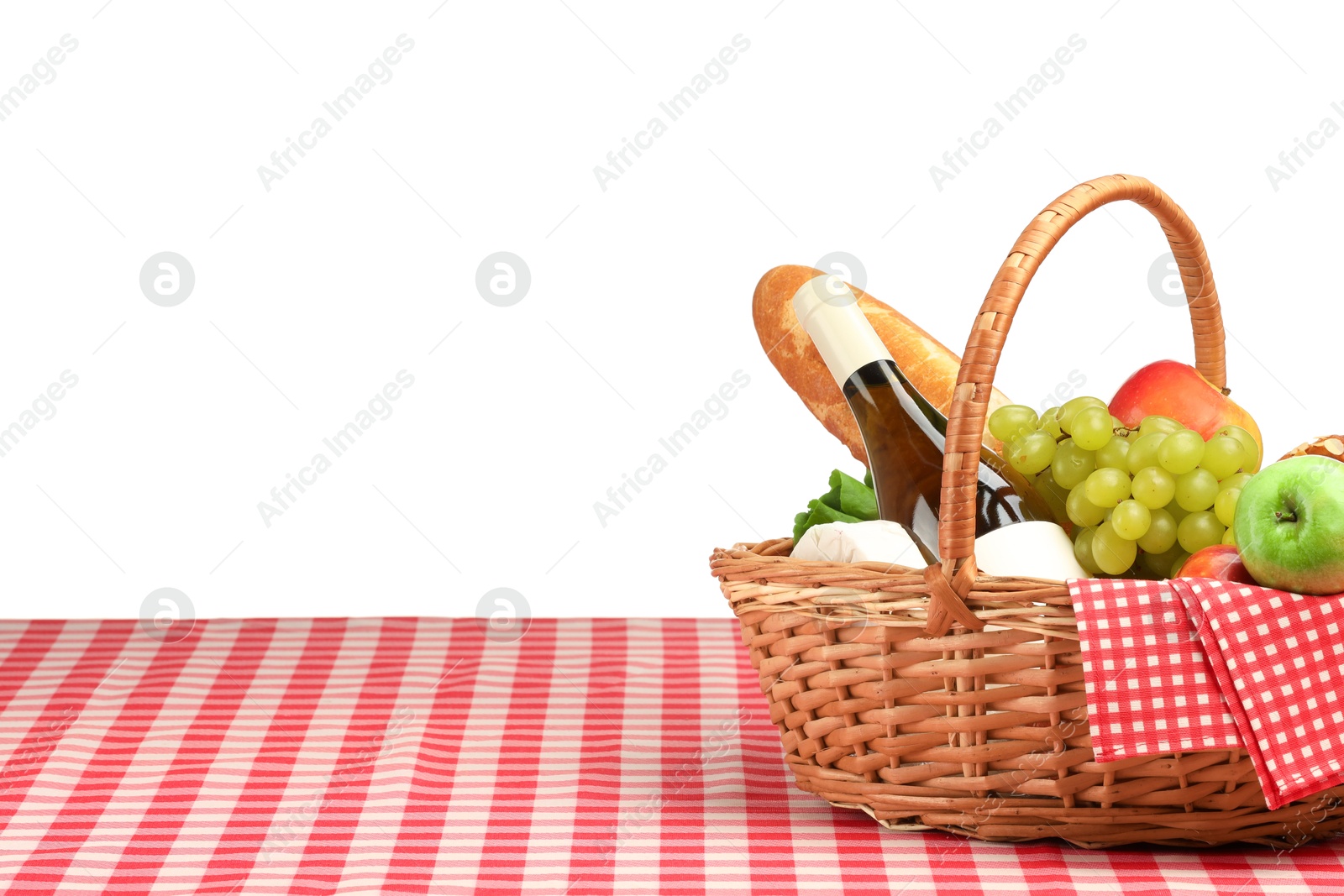 Photo of Picnic wicker basket with food, bottle of wine and napkin on table against white background. Space for text