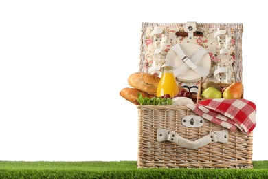 Photo of Picnic wicker basket with food, tableware and bottle of juice on grass against white background. Space for text