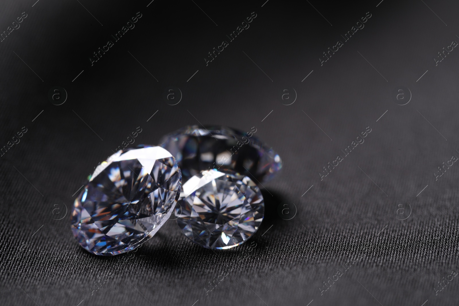 Photo of Many beautiful shiny diamonds on black fabric, closeup