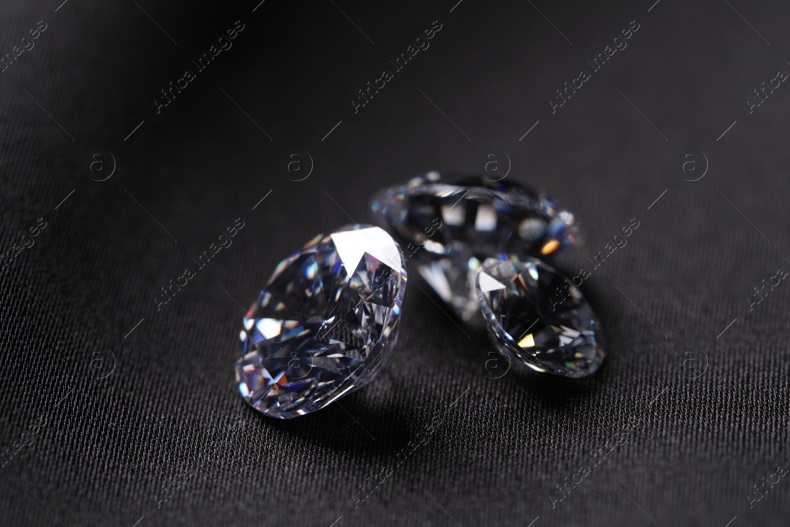 Photo of Many beautiful shiny diamonds on black fabric, closeup