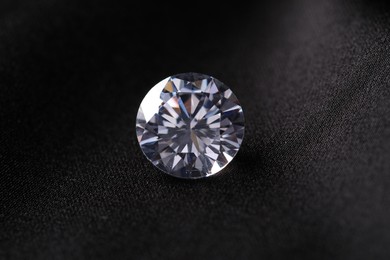 One beautiful shiny diamond on black fabric, closeup