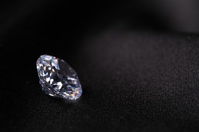 One beautiful shiny diamond on black fabric, closeup. Space for text