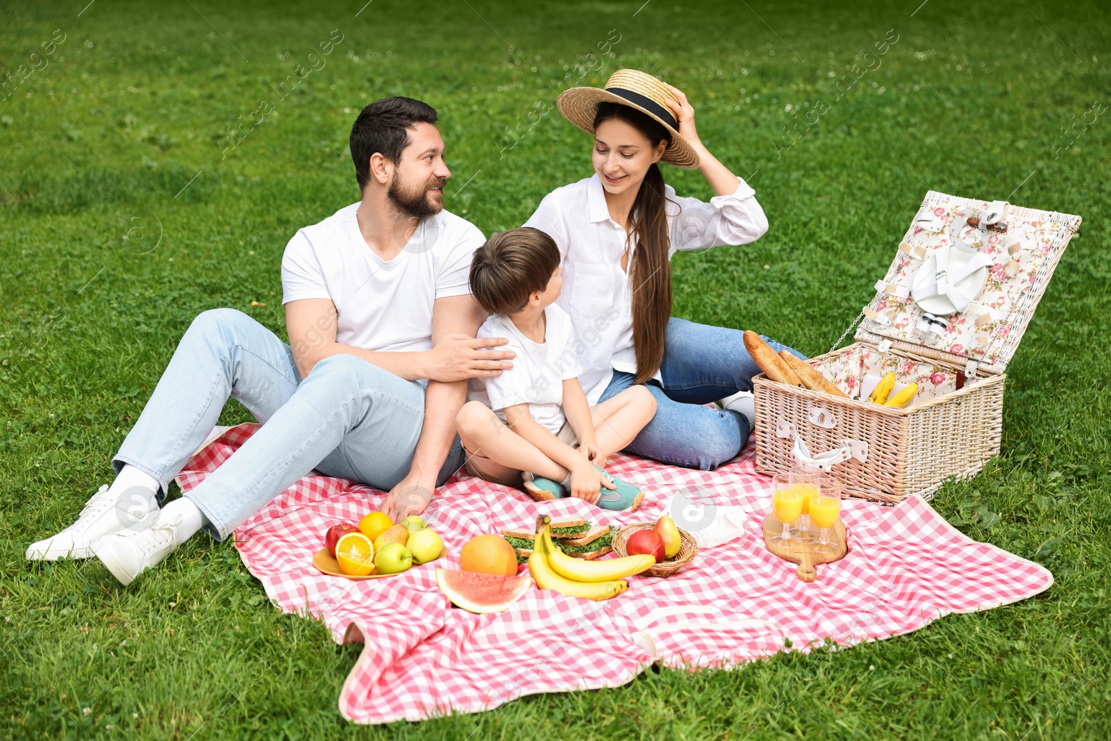 Photo of Family picnic. Happy parents and their son spending time together in park