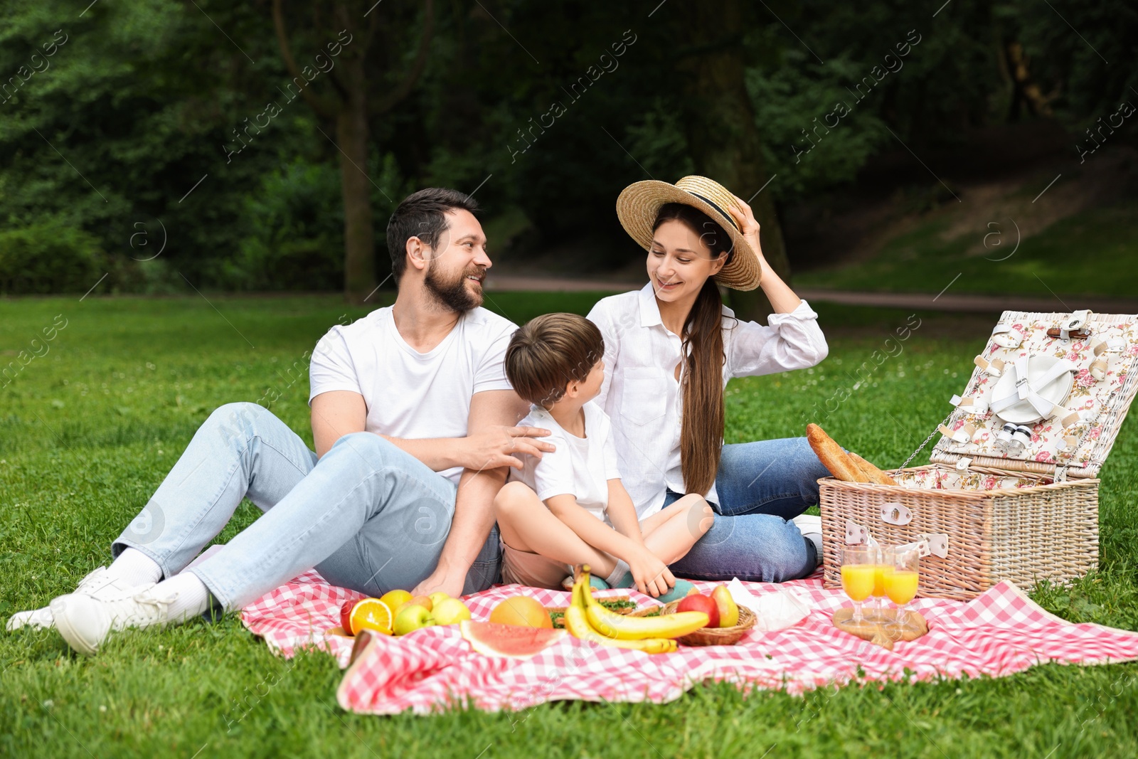 Photo of Family picnic. Happy parents and their son spending time together in park