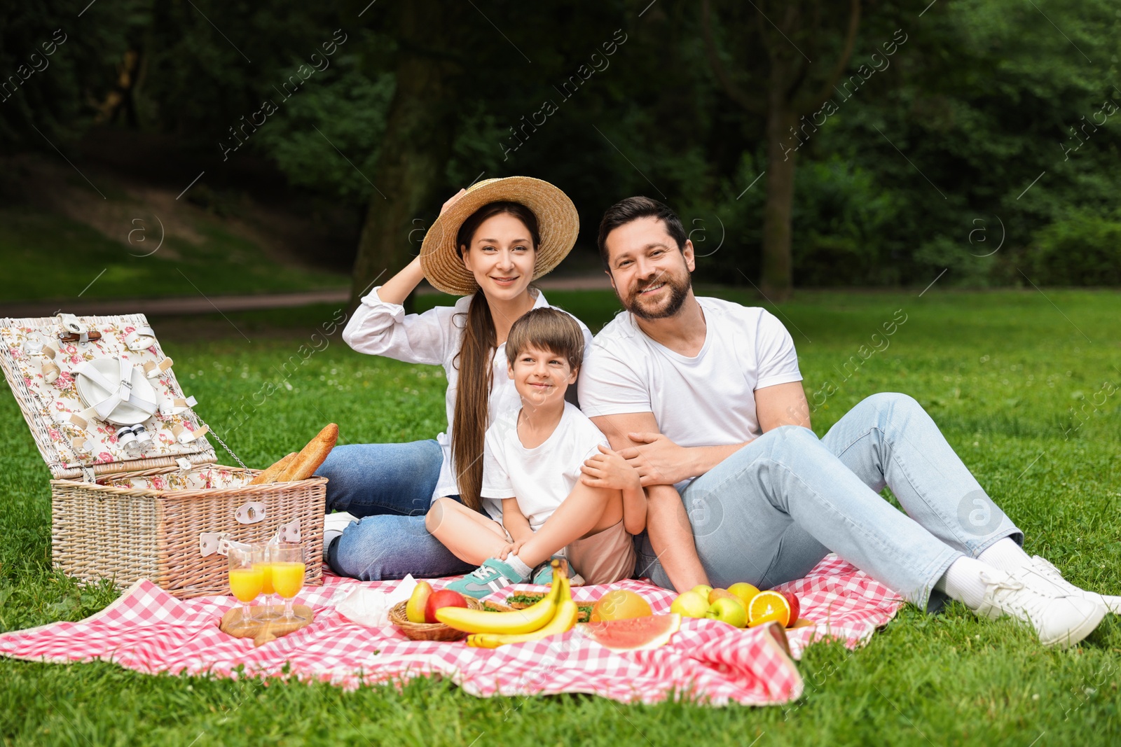 Photo of Family picnic. Happy parents and their son spending time together in park