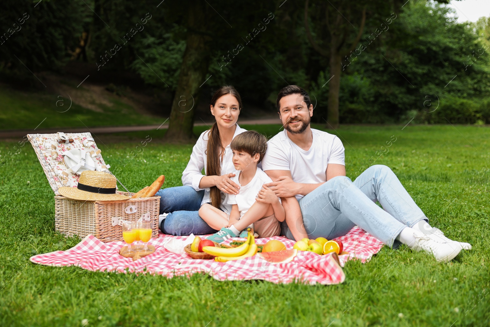 Photo of Family picnic. Happy parents and their son spending time together in park