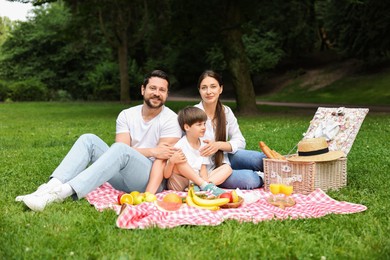 Photo of Family picnic. Happy parents and their son spending time together in park