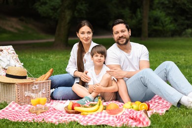 Photo of Family picnic. Happy parents and their son spending time together in park