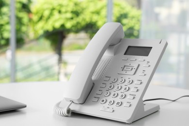 Photo of White telephone on table in office. Space for text