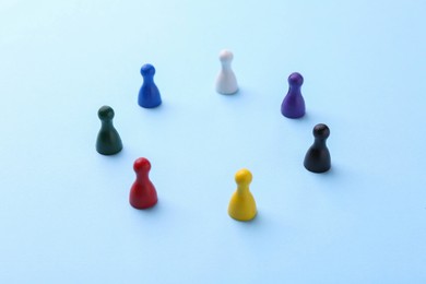 Photo of Equality concept. Different game pieces on light blue background