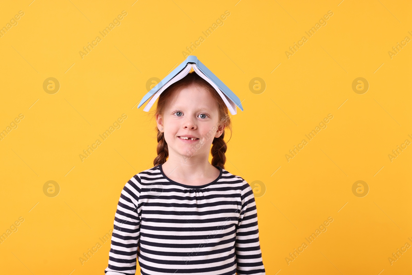 Photo of Smiling girl with book on yellow background