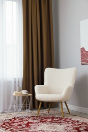 Photo of Soft armchair, side table and window with curtains indoors. Interior design