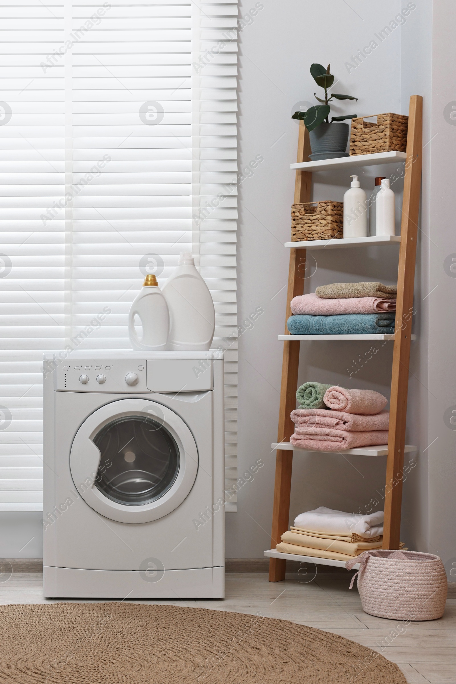 Photo of Washing machine, detergents, towels and shelving unit in laundry room