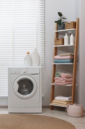 Photo of Washing machine, detergents, towels and shelving unit in laundry room