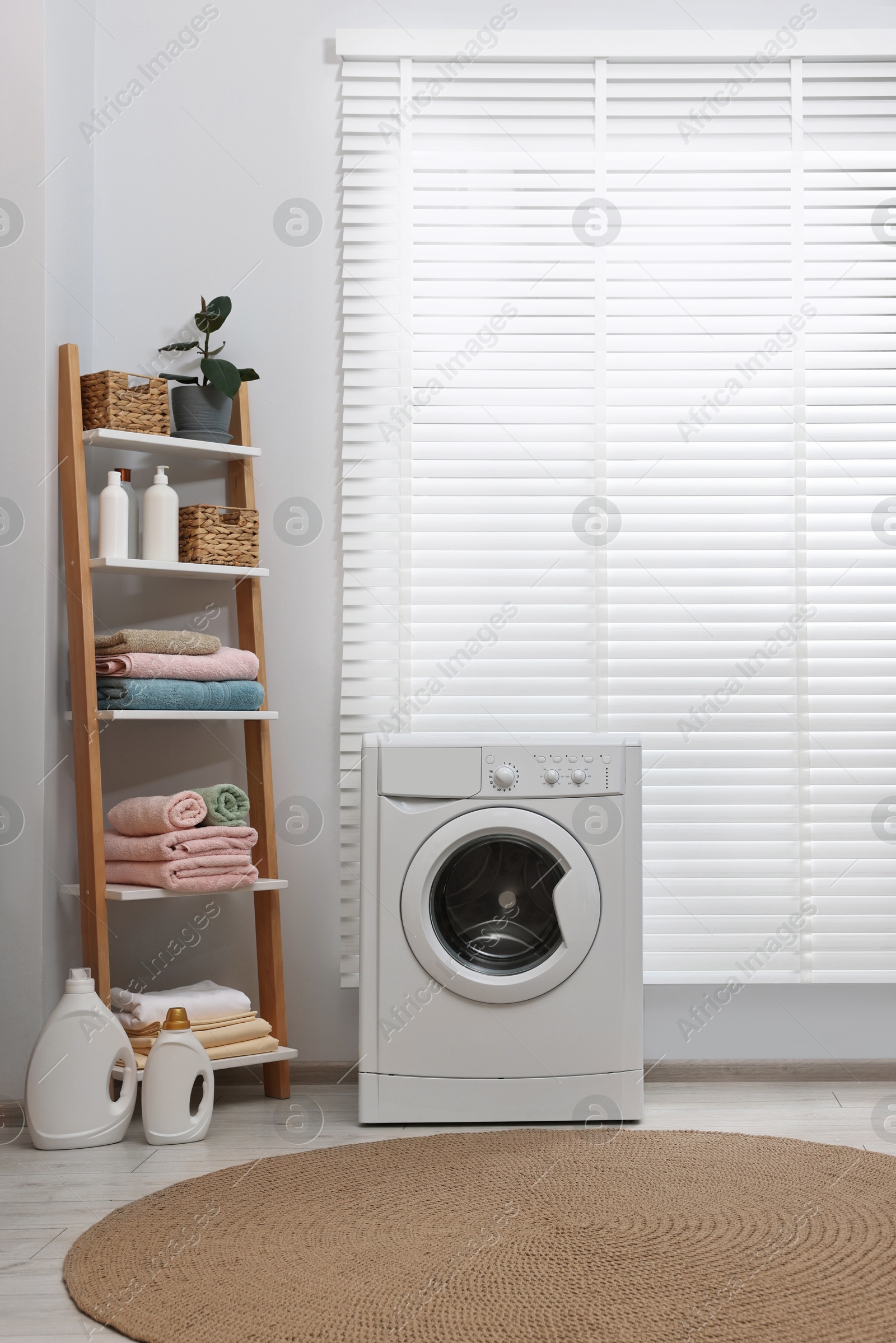 Photo of Washing machine, detergents, towels and shelving unit in laundry room