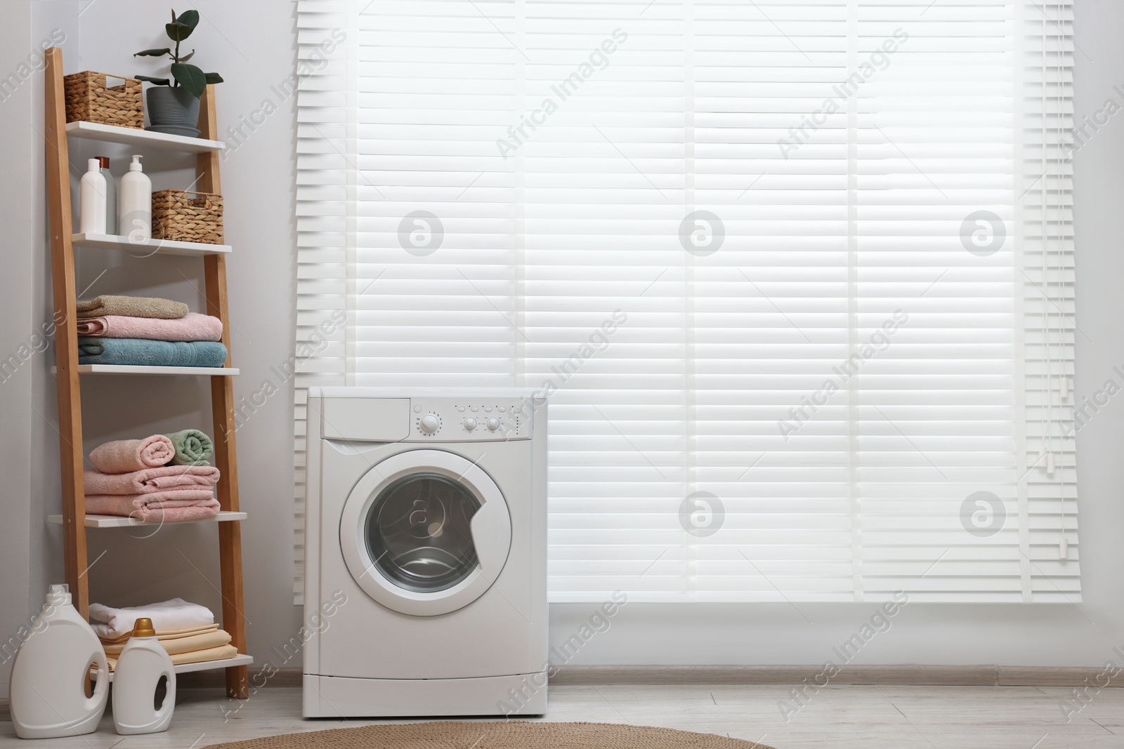 Photo of Washing machine, detergents, towels and shelving unit in laundry room