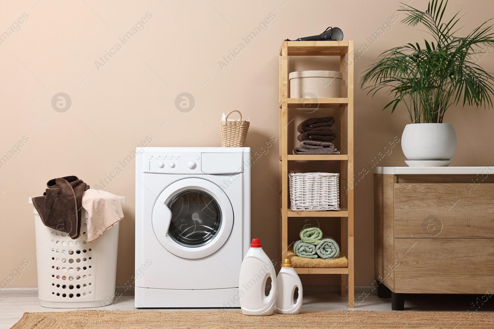 Photo of Stylish laundry room interior with washing machine, furniture and houseplant