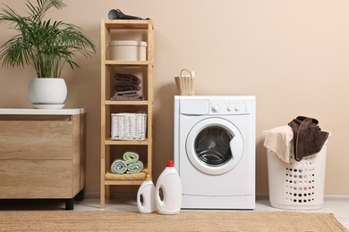 Photo of Stylish laundry room interior with washing machine, furniture and houseplant