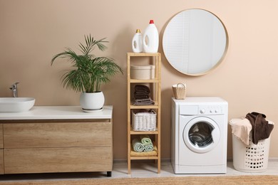 Stylish laundry room interior with washing machine, vessel sink, houseplant and basket