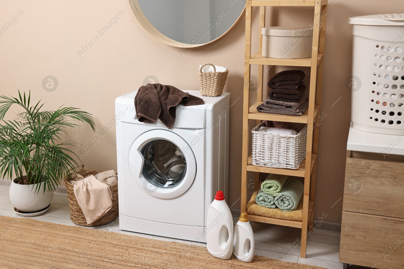 Photo of Stylish laundry room interior with washing machine, furniture and houseplant