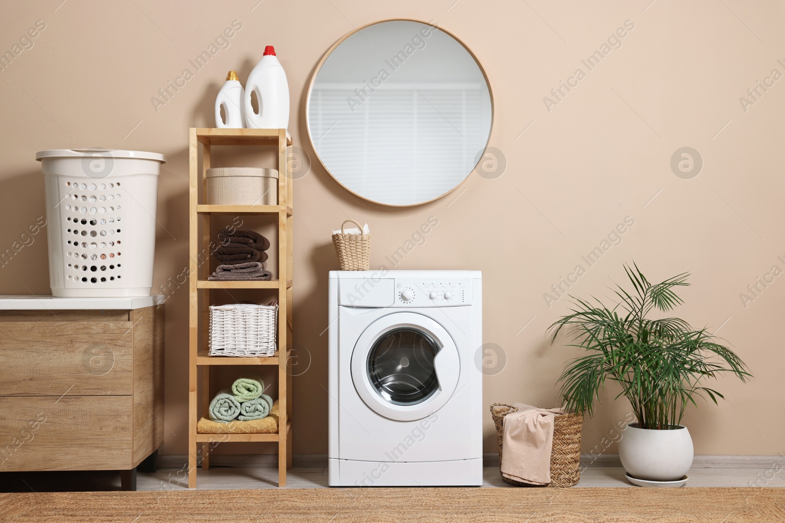 Photo of Stylish laundry room interior with washing machine, furniture and houseplant